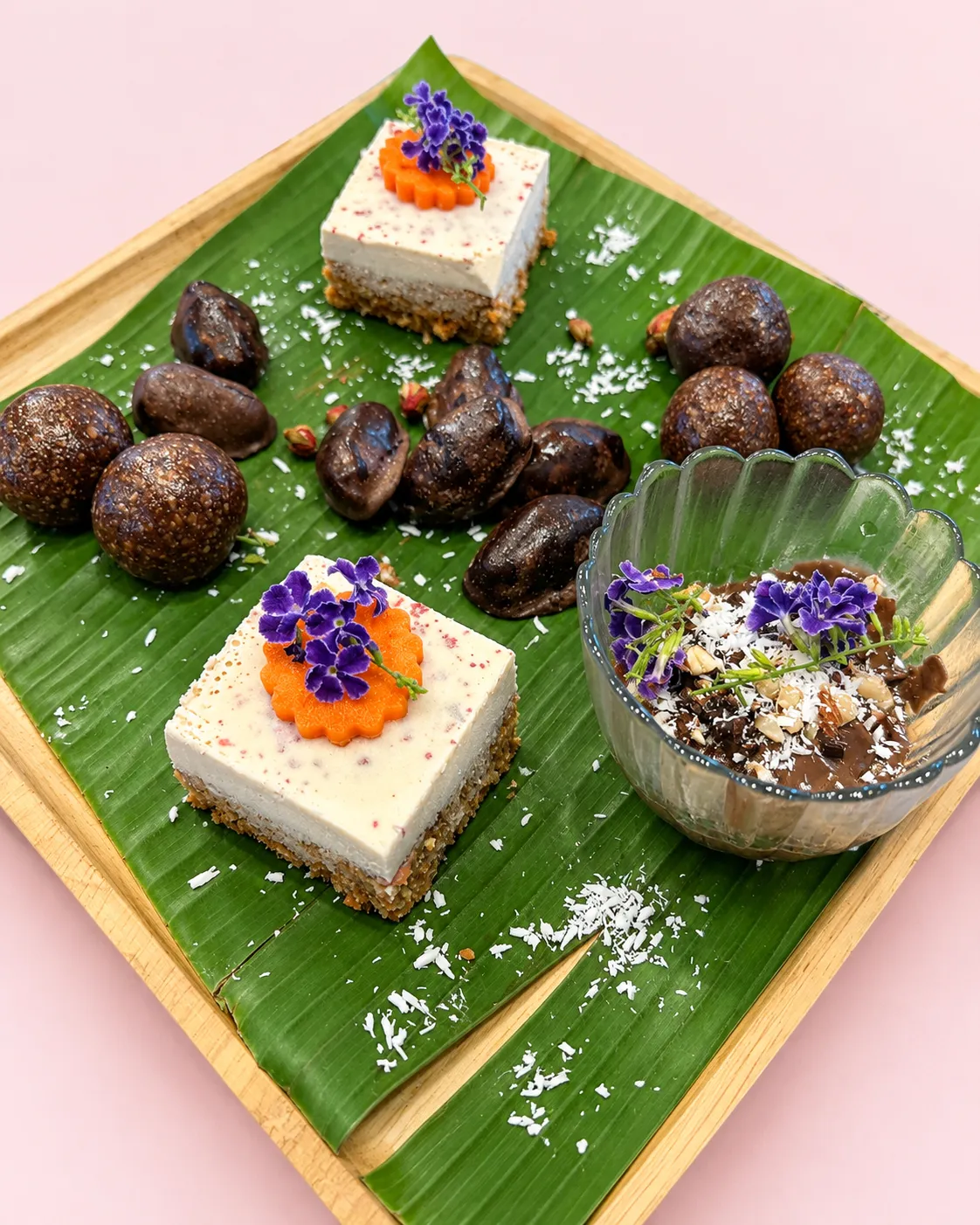 Raw carrot cake, chocolate pecan energy bites, chocolate-covered dates and chocolate avocado mousse on a banana leaf